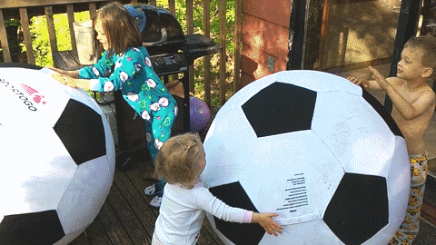 Kids play with giant soccer balls